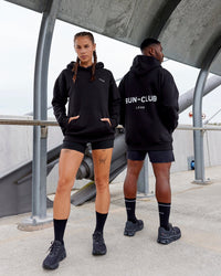 Duo wearing Unisex RUN-CLUB Hoodie Oversize - Black | Thumbnail Index: 0