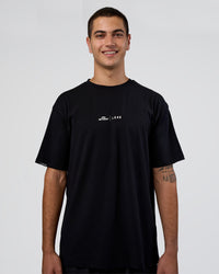 Man wearing Movember 2025 FLXCotton Oversize Tee - Black | Model:Zoran | Size:M | Thumbnail Index: 2