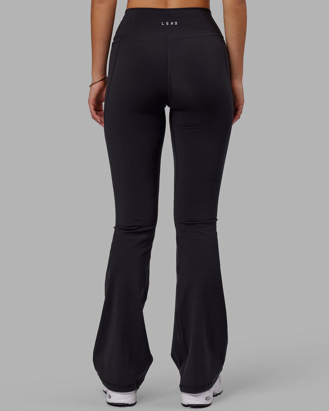 Woman wearing Fusion Ultra High-Rise Flared Legging Pockets - Black | Model:Milly | Size:S - view 4