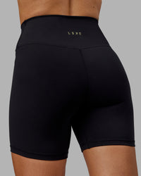 Woman wearing Sara Strike Ultra High-Rise Cross Over Waist 6" Short - Black | Thumbnail Index: 6