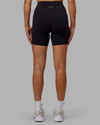 Woman wearing Sara Strike Ultra High-Rise Cross Over Waist 6" Short - Black | Thumbnail Index: 3