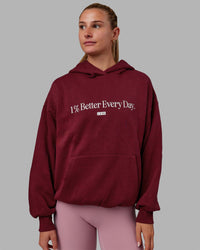 Woman wearing Unisex 1% Better Hoodie Oversize - Cranberry-White | Thumbnail Index: 1