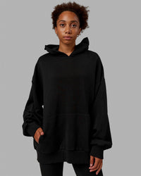 Woman wearing Unisex MVP Hoodie Oversize - Black | Thumbnail Index: 3