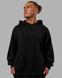 Man wearing Unisex MVP Hoodie Oversize - Black | Thumbnail Index: 0