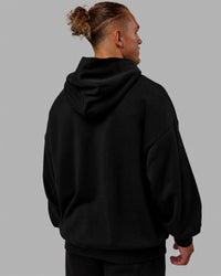 Man wearing Unisex MVP Hoodie Oversize - Black | Thumbnail Index: 4