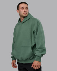 Man wearing Unisex MVP Hoodie Oversize - Sage Brush | Thumbnail Index: 1
