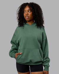 WOman wearing Unisex MVP Hoodie Oversize - Sage Brush | Thumbnail Index: 2