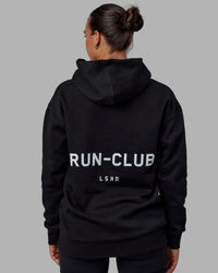 Woman wearing Unisex RUN-CLUB Hoodie Oversize - Black | Thumbnail Index: 3