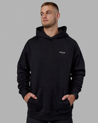 Man wearing Unisex RUN-CLUB Hoodie Oversize - Black | Thumbnail Index: 1