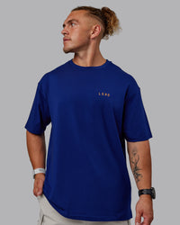 Man wearing Unisex Strike Through FLXCotton Tee Oversize - Midnight Blue-Vibrant Orange | Thumbnail Index: 5