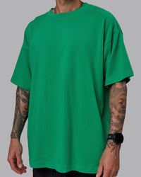 Man wearing Unisex We Rise Heavyweight Tee Oversize - Impact Green-White | Thumbnail Index: 8