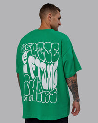 Man wearing Unisex We Rise Heavyweight Tee Oversize - Impact Green-White | Thumbnail Index: 3
