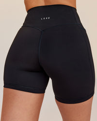 Woman wearing Fusion V-Contour Ultra High-Rise 6" Short Pockets - Black | Model:Rhiley | Size:S | Thumbnail Index: 1