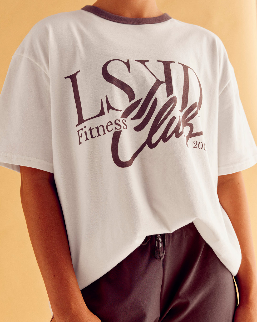 Woman wearing LSKD Fitness Club Heavyweight Oversized Tee - Off White-Cocoa Powder | Model:Charlize | Size:S - view 1