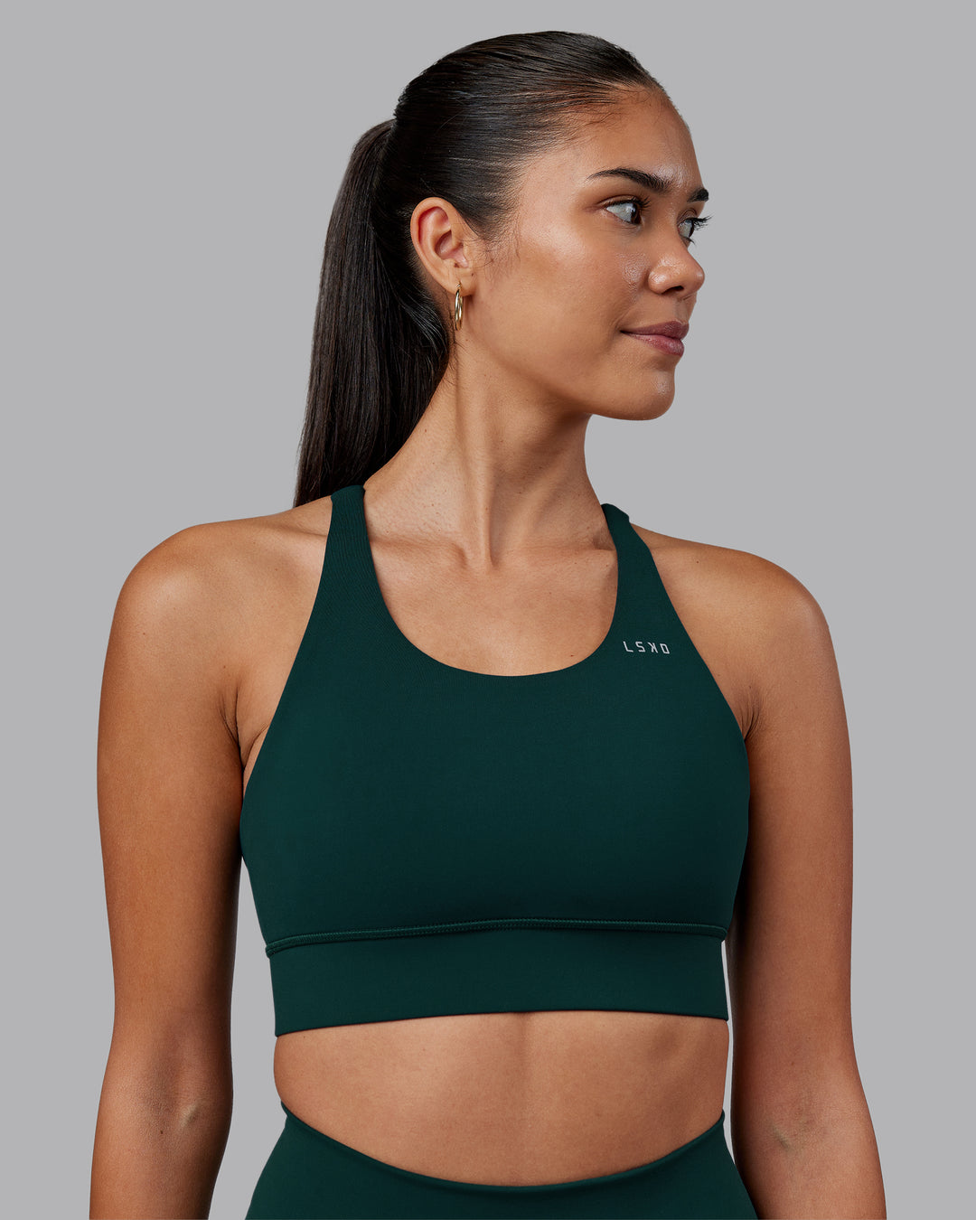 Woman wearing Accelerate Sports Bra - Dark Moss | Set:true | Angle:front | Model:Rhiley | Size:S - view 1