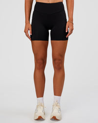 Woman wearing Elite Run High-Rise 5" Short Pockets - Black | Model:Emelia | Size:S | Thumbnail Index: 1