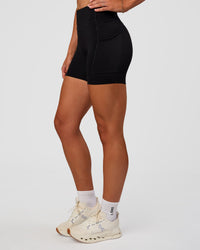 Woman wearing Elite Run High-Rise 5" Short Pockets - Black | Model:Emelia | Size:S | Thumbnail Index: 9