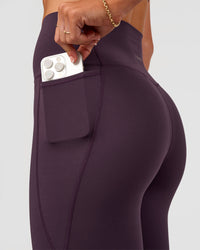 Woman wearing Elixir Ultra High-Rise 7/8 Legging Pockets - Midnight Plum | Model:Emelia | Size:S | Thumbnail Index: 1