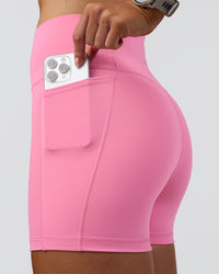 Woman wearing Fusion Ultra High-Rise 4" Short Pockets - Candy Pink | Set:true | Angle:closeup | Model:Emelia | Size:S | Thumbnail Index: 1