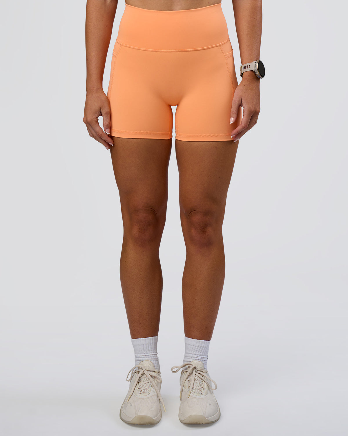 Woman wearing Fusion Ultra High-Rise 4" Short Pockets - Cantaloupe | Set:true | Angle:front | Model:Emelia | Size:S