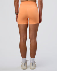 Woman wearing Fusion Ultra High-Rise 4" Short Pockets - Cantaloupe | Set:true | Angle:back | Model:Emelia | Size:S | Thumbnail Index: 2