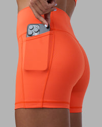 Woman wearing Fusion Ultra High-Rise 4" Short Pockets - Ultra Orange | Set:true | Angle:closeup | Model:Katie | Size:S | Thumbnail Index: 0