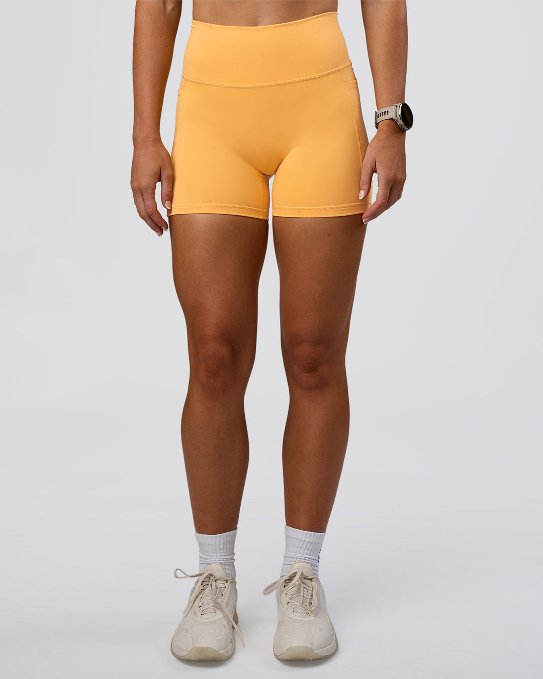 Woman wearing Fusion Ultra High-Rise 4" Short Pockets - Warm Apricot | Set:true | Angle:front | Model:Emelia | Size:S - view 7