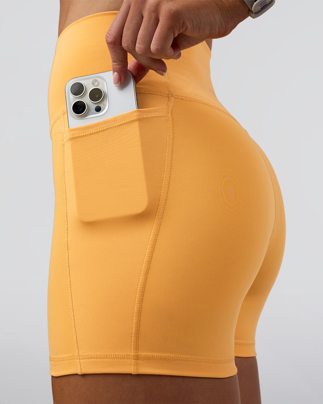 Woman wearing Fusion Ultra High-Rise 4" Short Pockets - Warm Apricot | Set:true | Angle:closeup | Model:Emelia | Size:S - view 5