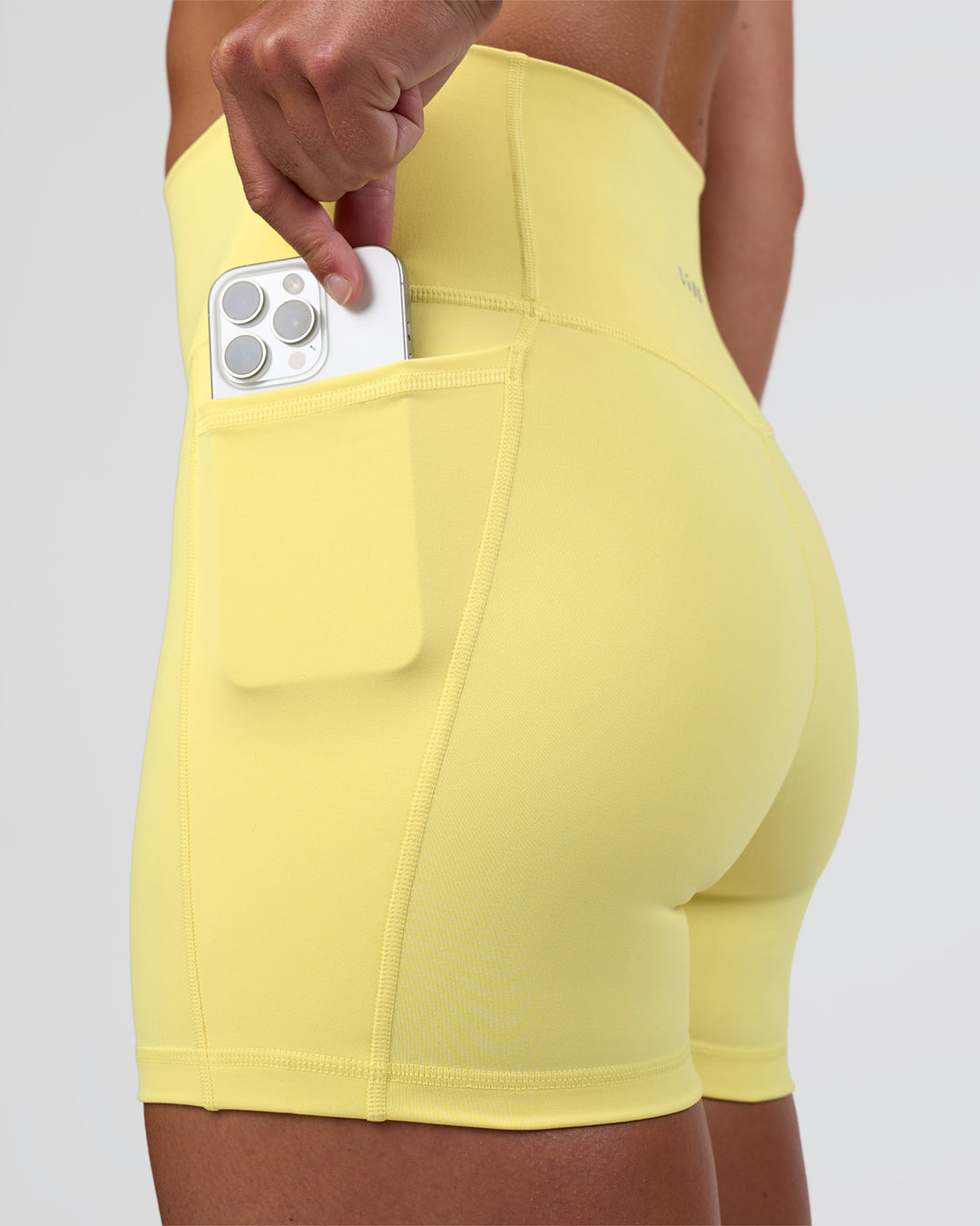 Woman wearing Fusion Ultra High-Rise 4" Short Pockets - Yellow Fizz | Set:true | Angle:closeup | Model:Sav | Size:S - view 1