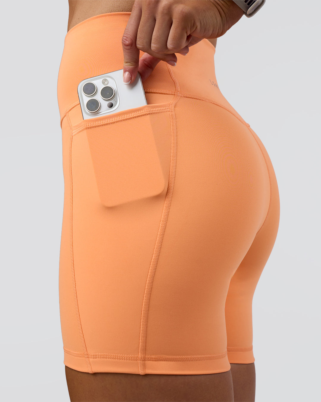 Woman wearing Fusion Ultra High-Rise 6" Short Pockets - Cantaloupe | Set:true | Angle:closeup | Model:Emelia | Size:S - view 2