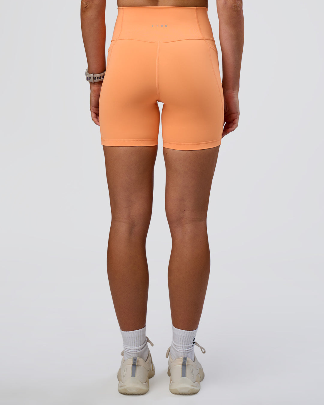 Woman wearing Fusion Ultra High-Rise 6" Short Pockets - Cantaloupe | Set:true | Angle:back | Model:Emelia | Size:S - view 4