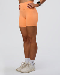 Woman wearing Fusion Ultra High-Rise 6" Short Pockets - Cantaloupe | Set:true | Angle:side | Model:Emelia | Size:S | Thumbnail Index: 6