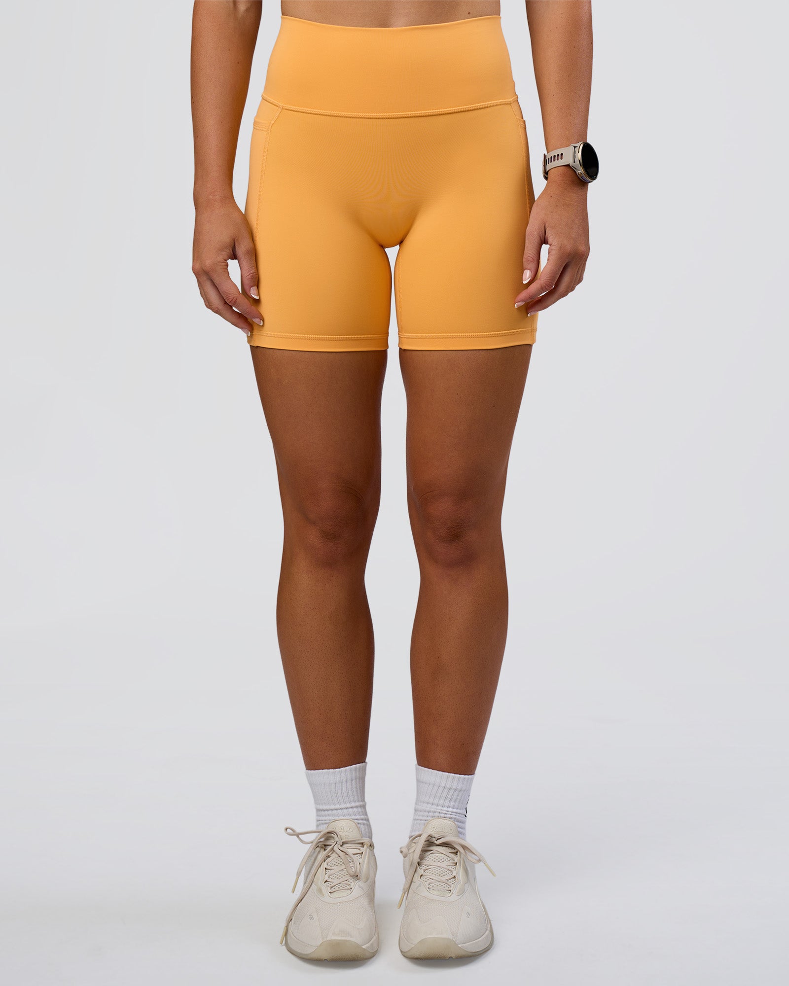 Woman wearing Fusion Ultra High-Rise 6" Short Pockets - Warm Apricot | Set:true | Angle:front | Model:Emelia | Size:S