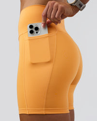 Woman wearing Fusion Ultra High-Rise 6" Short Pockets - Warm Apricot | Set:true | Angle:closeup | Model:Emelia | Size:S | Thumbnail Index: 1