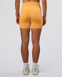 Woman wearing Fusion Ultra High-Rise 6" Short Pockets - Warm Apricot | Set:true | Angle:back | Model:Emelia | Size:S | Thumbnail Index: 3