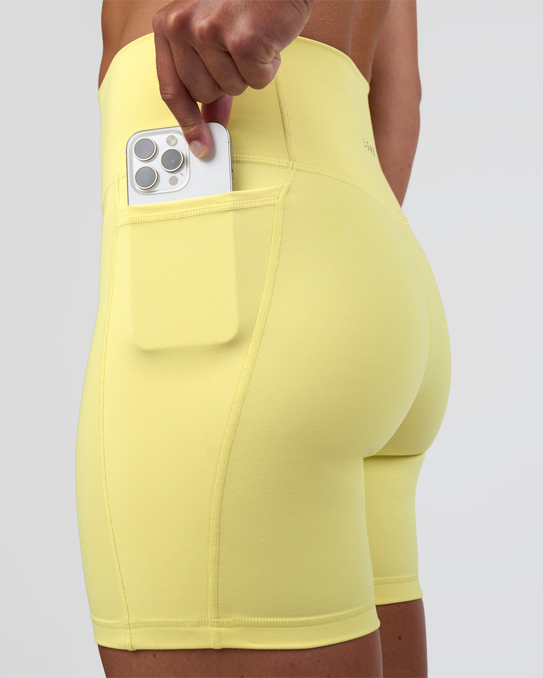 Woman wearing Fusion Ultra High-Rise 6" Short Pockets - Yellow Fizz | Set:true | Angle:closeup | Model:Sav | Size:S - view 5