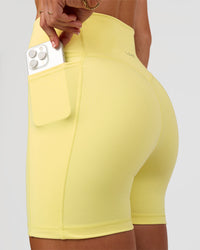 Woman wearing Fusion V-Contour Ultra High-Rise 4” Short Pockets - Yellow Fizz | Model:Emelia | Size:S | Thumbnail Index: 1
