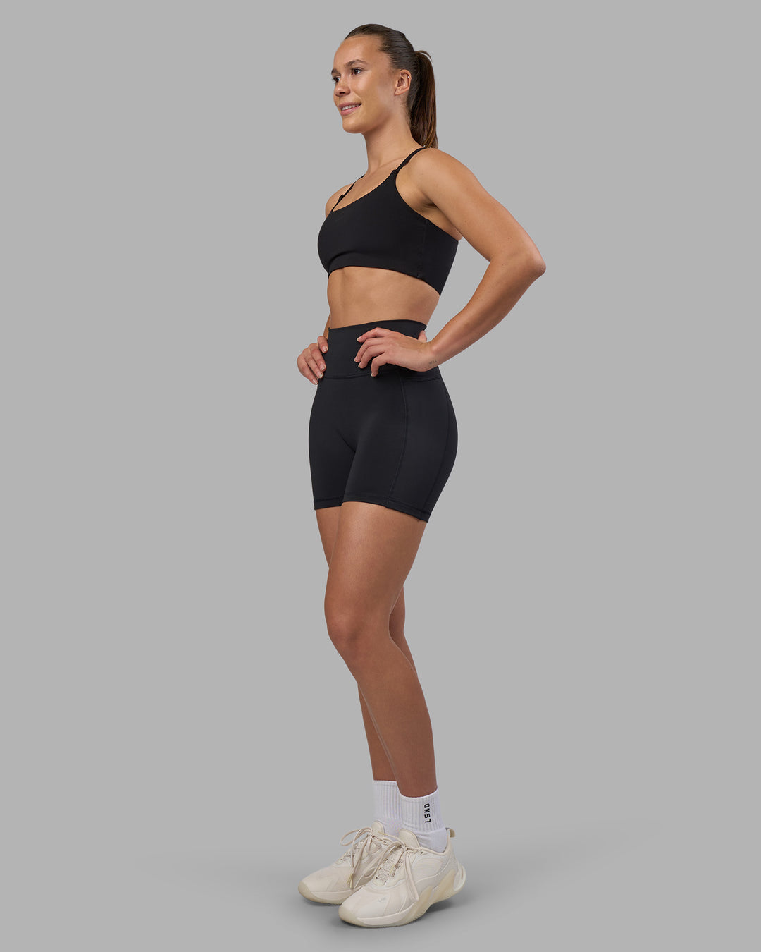 Woman wearing Fusion V-Contour Ultra High-Rise 4” Short Pockets - Black | Model:Charlize | Size:S - view 3