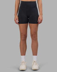 Woman wearing Fusion V-Contour Ultra High-Rise 4” Short Pockets - Black | Model:Charlize | Size:S | Thumbnail Index: 1