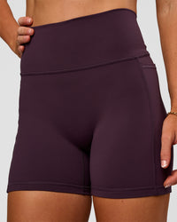 Woman wearing Fusion V-Contour Ultra High-Rise 4” Short Pockets - Midnight Plum | Model:Emelia | Size:S | Thumbnail Index: 6