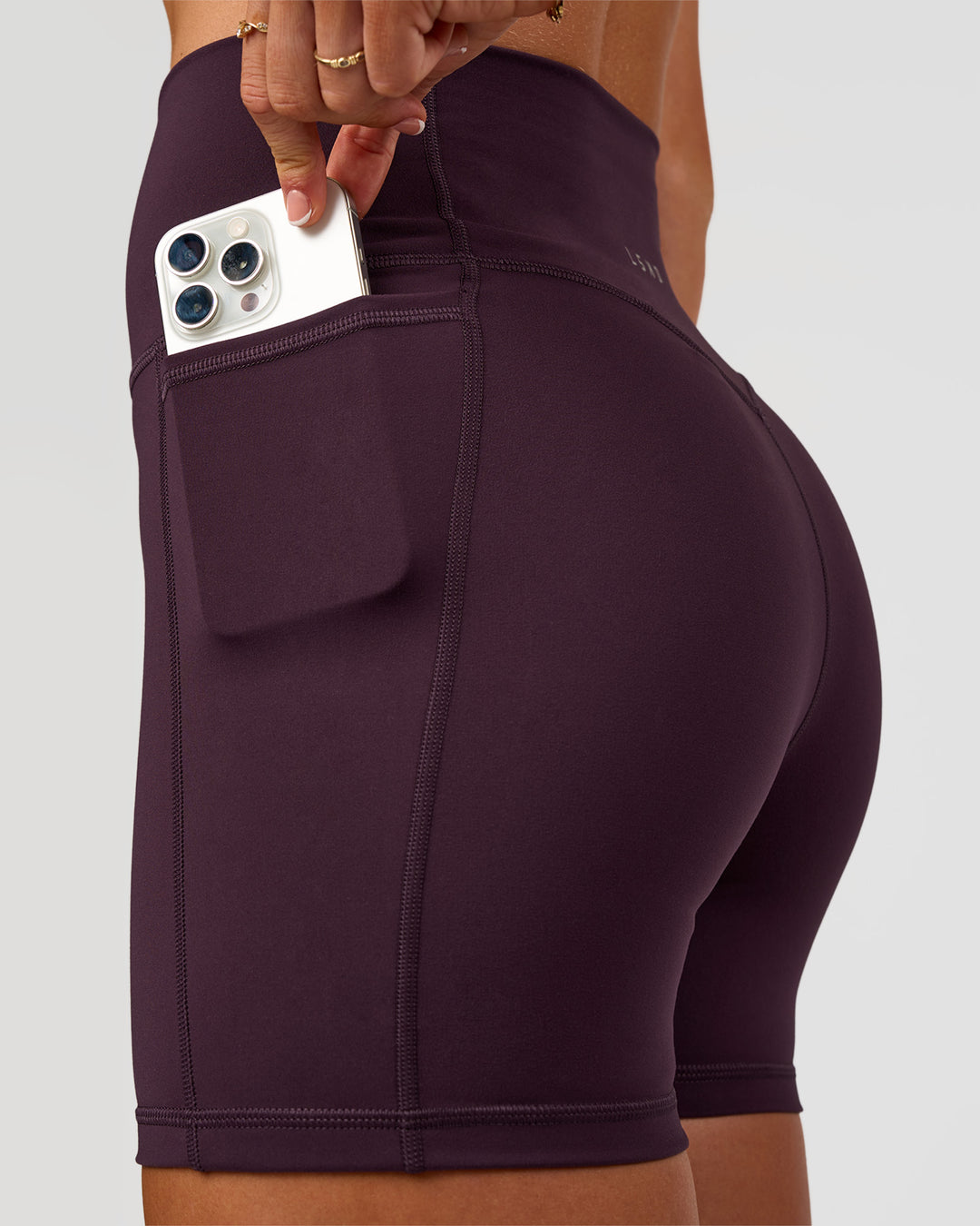 Woman wearing Fusion V-Contour Ultra High-Rise 4” Short Pockets - Midnight Plum | Model:Emelia | Size:S - view 3