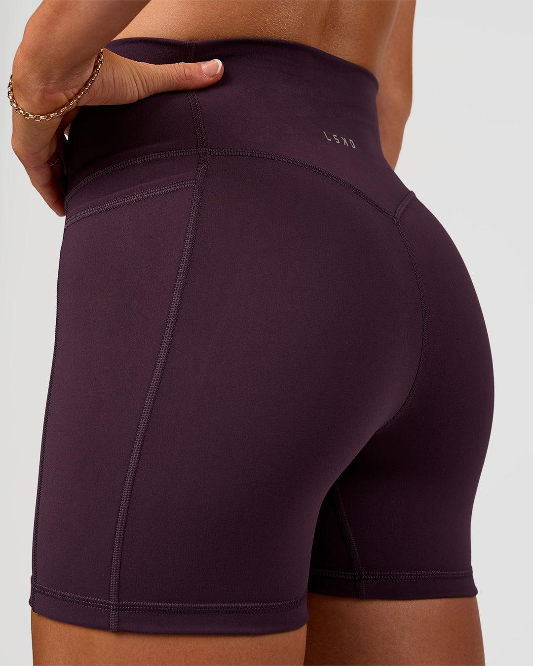 Woman wearing Fusion V-Contour Ultra High-Rise 4” Short Pockets - Midnight Plum | Model:Emelia | Size:S - view 2