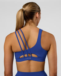 Woman wearing Galvanise Sports Bra 2.0 - Electric Indigo | Set:true | Angle:back | Model:Evie | Size:S | Thumbnail Index: 1
