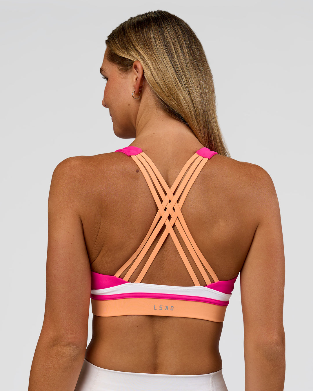 Woman wearing Revitalise Flash Sports Bra - Ultra Pink-Cantaloupe-White | Model:Amity | Size:S - view 1