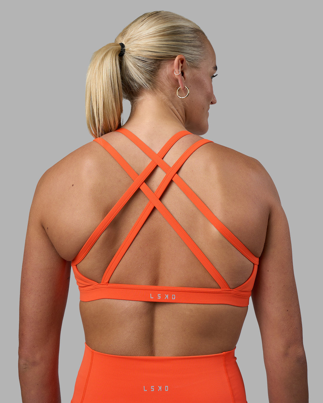 Woman wearing Velocity Sports Bra - Ultra Orange | Model:Katie | Size:S - view 1