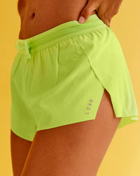 Woman wearing Accelerate 3" Mid-Rise Running Short - Hyper Green | Model:Txai | Size:XS | Thumbnail Index: 0