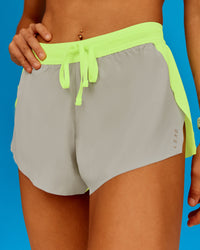 Woman wearing Accelerate 3" Running Short - Lime Glo-Shale Beige | Model:Steph | Size:XS | Thumbnail Index: 1