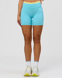 Woman wearing Lume Fusion Mid-Rise V Contour 6" Short Pockets - Baltic Sea-Lemon | Model:Grace | Size:XS | Thumbnail Index: 5