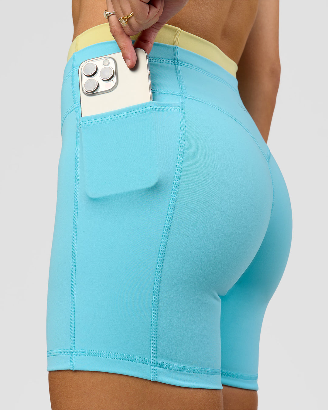 Woman wearing Lume Fusion Mid-Rise V Contour 6" Short Pockets - Baltic Sea-Lemon | Model:Grace | Size:XS - view 3