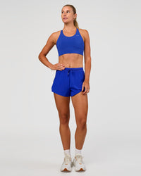 Woman wearing Accelerate Split Strap Sports Bra - Electric Indigo | Model:Emelia | Size:XS | Thumbnail Index: 8